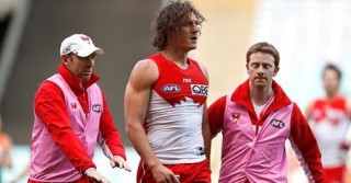Kurt Tippett leaves the field with Sydney Swans physio, Tim Needham